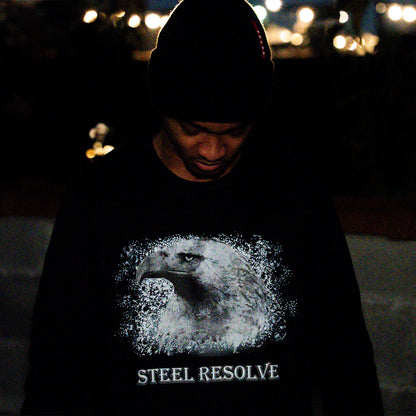 Person wearing a black longsleeve with an eagle design and 'Steel Resolve' text at night.